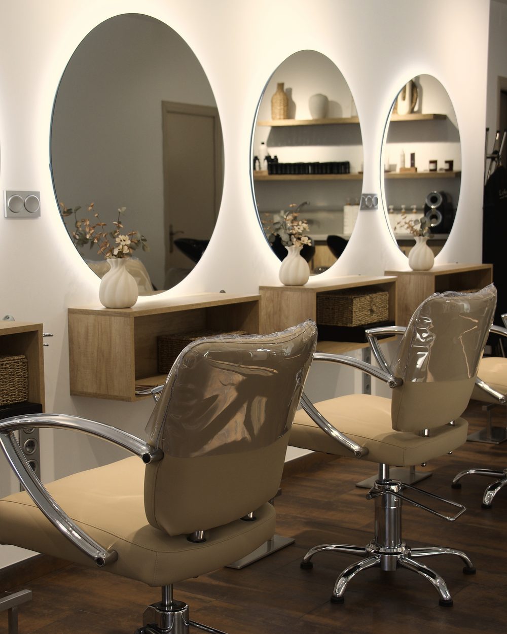 El salón de Eva Arenas: tres espejos ovalados retroiluminados, muebles de madera clara y suelo de madera